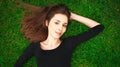 Top view portrait of a young beautiful woman in black dress lies on green lawn in a park Royalty Free Stock Photo