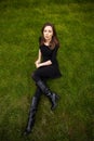 Top view portrait of a young beautiful woman in black dress lies on green lawn in a park Royalty Free Stock Photo