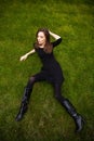 Top view portrait of a young beautiful woman in black dress lies on green lawn in a park Royalty Free Stock Photo