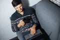 Top view portrait of young confident man with black mug in hand, sitting home on sofa and using laptop. Royalty Free Stock Photo