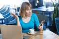 Top view portrait of young shocked blonde woman in blue t-shirt, sitting in cafe and holding her mobile smart phone and looking Royalty Free Stock Photo