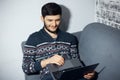 Top view portrait of young smiling man, sitting home on sofa, looking in laptop and using touchpad. Royalty Free Stock Photo