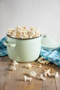 Top view of pot with fresh popcorn on rustic wooden table with blue cloth, white background Royalty Free Stock Photo