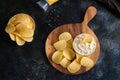 Top view potato chips, sauce in a white bowl, peppers on a wooden cutting board Royalty Free Stock Photo