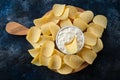 Top view potato chips, sauce in a white bowl on a wooden cutting board