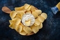 Top view potato chips, sauce in a white bowl on a wooden cutting board