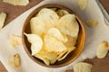 Top view of potato chips in wooden bowl putting on linen and wooden background