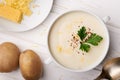 Top view potato soup with cheese and raw potatoes on the table