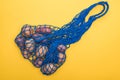 Top view of potatoes in blue string bag isolated on yellow. Royalty Free Stock Photo