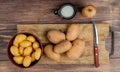 top view of potatoes in bowl and on cutting board with knife and salt on wooden background Royalty Free Stock Photo