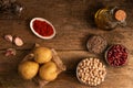 Top view of potatoes, 3 bowls of chickpea, red beans and lentil and other ingredients on the table