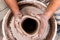 Top view of potter`s hand making a vase of white clay on throwing-wheel in ceramics studio, concept of creativity and art,