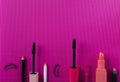 Top view of mascara, lipsticks, eyelashes, lip pencils on the bright pink background.Empty space for text