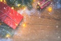 Top view of presents, pine tree branches, Christmas balls and lights on wooden background with snow overlay Royalty Free Stock Photo