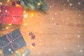 Top view of presents, pine tree branches, Christmas balls and lights on wooden background with snow overlay Royalty Free Stock Photo