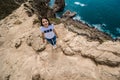 top view of pretty woman in a white t-shirt and blue jeans standing on the rocky edge of the cliff. The waves of the ocean break Royalty Free Stock Photo