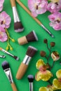 Vertical image of decorative green and pink orchid flowers,makeup brushes on the green background Royalty Free Stock Photo