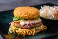 Top view of a Ramen burger with a crispy shrimp patty and wasabi mayo on a colorful plate