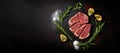 Top view of raw beef steak lying on a dark background. Piece of meat on chalkboard, schist stone. Spices and herbs around.