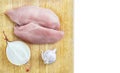 Top View of Raw Chicken Breasts, Fillets on a Wooden Cutting Board with Half Onion, Whole Garlic Bulb Isolated On White Background Royalty Free Stock Photo