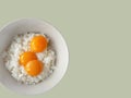 top view of 3 raw eggs over cooked rice, preparing for fried rice menu, home cooking on color background with copy space and Royalty Free Stock Photo