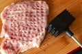 Top view of raw meat slice and iron meat tenderizer on wooden cutting board Royalty Free Stock Photo