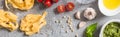 Top view of raw Pappardelle near tomatoes, garlic, basil, pine nuts, olive oil, water and pesto sauce on grey surface, panoramic Royalty Free Stock Photo
