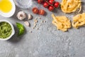 Top view of raw Pappardelle near tomatoes, garlic, basil, pine nuts, olive oil, water and pesto sauce on grey surface Royalty Free Stock Photo