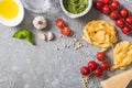 Top view of raw Pappardelle near tomatoes, garlic, basil, pine nuts, olive oil, water and pesto sauce on grey surface Royalty Free Stock Photo