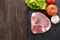 Top view raw pork on blackboard and vegetables on wooden background
