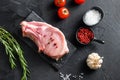 Top view raw pork chop steak and salt, pepper on black slate stone board with rosemary, and fresh ingredients for grill over black Royalty Free Stock Photo