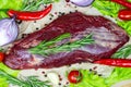 Top view of raw red beef meat with green rosemary and fresh vegetables on light wooden cutting board background. Royalty Free Stock Photo