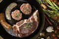 Top view of raw seasoned steak meat beef sausages on a pan with vegetables on a wooden table