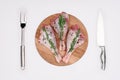 top view of raw turkey legs with pepper corns and rosemary on cutting board with fork and knife Royalty Free Stock Photo