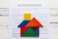 Top view real estate purchase contact with tangram shaped as house