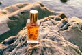 Top view of rectangular glass bottle with golden perfume at rocks. Fragrance marketing