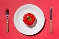 Top view of red bell pepper on white plate with knife and fork o Royalty Free Stock Photo