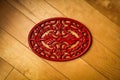 Top view of a red cast iron trivet on a wooden surface Royalty Free Stock Photo