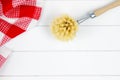 Top-view of red checkered tea towel and dishwashing brush