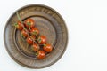 Top view of red cherry tomatoes bunch with water drops on brown plate isolated on a white background. Close up view Royalty Free Stock Photo