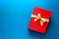 Top view on red Christmas gift box decorated with ribbon on blue paper background. Royalty Free Stock Photo