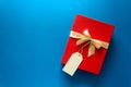 Top view on red Christmas gift box decorated with ribbon on blue paper background. Royalty Free Stock Photo