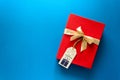 Top view on red Christmas gift box decorated with ribbon on blue paper background. New Year, holidays and celebration decorations Royalty Free Stock Photo