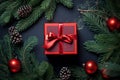 Top view of red Christmas gift box surrounded by fir branches and tre baubles