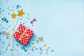 Top view of a red dotted gift box, golden magic wands, colorful confetti and ribbons over blue background. Celebration concept. Co Royalty Free Stock Photo