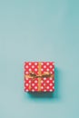 Top view of a red dotted gift box tied with golden bow over blue background. Vintage effect. Copy space.