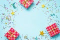 Top view of a red dotted gift boxes, golden magic wands, colorful confetti and ribbons over blue background. Celebration concept. Royalty Free Stock Photo