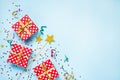 Top view of a red dotted gift boxes, golden magic wands, colorful confetti and ribbons over blue background. Celebration concept. Royalty Free Stock Photo