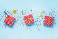 Top view of a red dotted gift boxes, golden magic wands, colorful confetti and ribbons over blue background. Celebration concept. Royalty Free Stock Photo