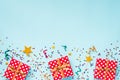 Top view of a red dotted gift boxes, golden magic wands, colorful confetti and ribbons over blue background. Celebration concept. Royalty Free Stock Photo